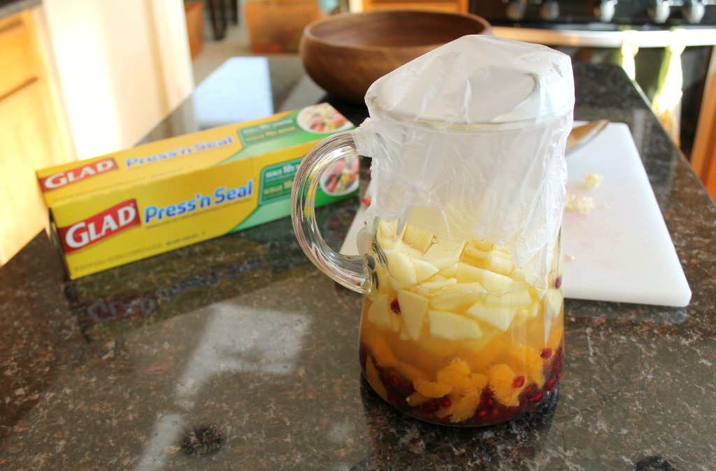 A large glass pitcher with wine and fruit covered with press'n seal plastic wrap.