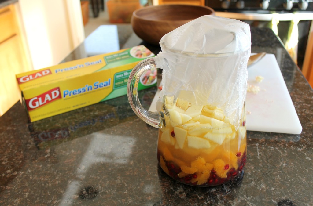 How to make a basic white wine sangria via SpanglishSpoon.com A large glass pitcher with wine and fruit covered with press'n seal plastic wrap.