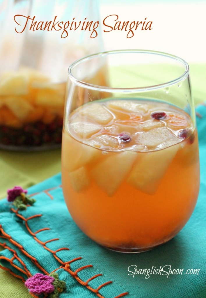 How to make a basic white wine sangria via SpanglishSpoon.com A glass of sangria with mixed fruit on a teal fabric napkin.