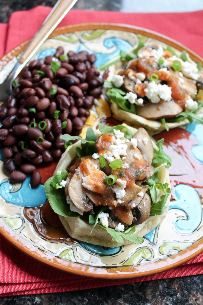 Homemade Sopes topped with baby arugula, spinach, requeson cheese, and red salsa.