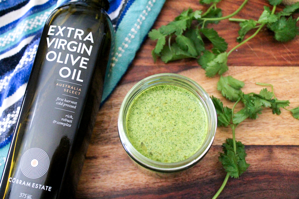 Dairy-Free Low-Fat Cilantro Dressing via SpanglishSpoon.com Extra virgin olive oil bottle next to a jar of a homemade Dairy-Free Low-Fat Cilantro Dressing