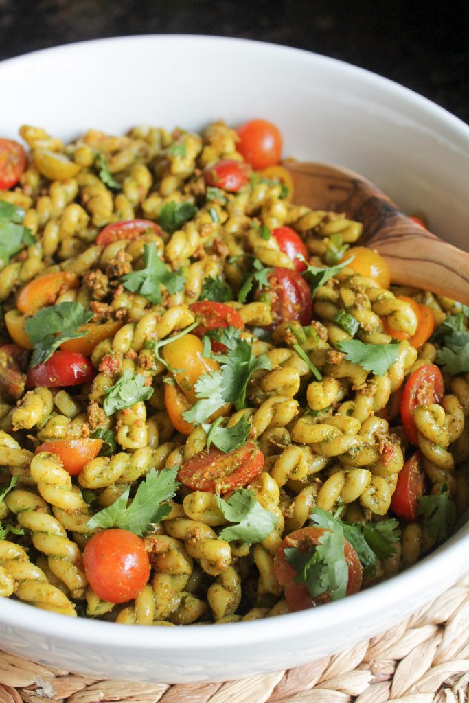 Pasta Salad with Cilantro Dressing and Longaniza in a white bowl with wooden serving spoon.