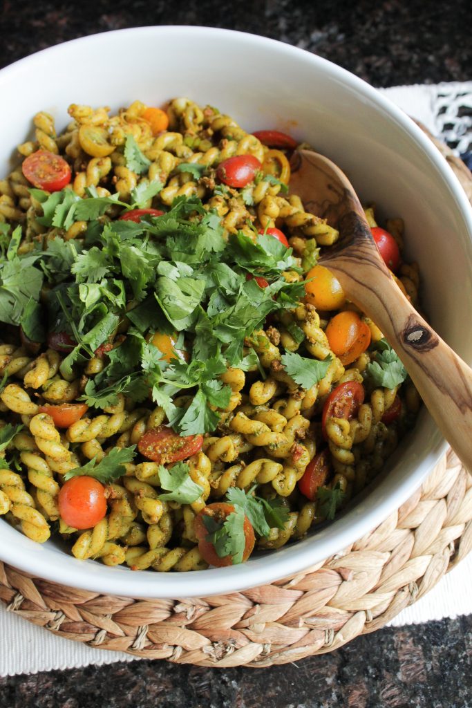 Pasta Salad with Cilantro Dressing and Longaniza in a white bowl with wooden serving spoon.