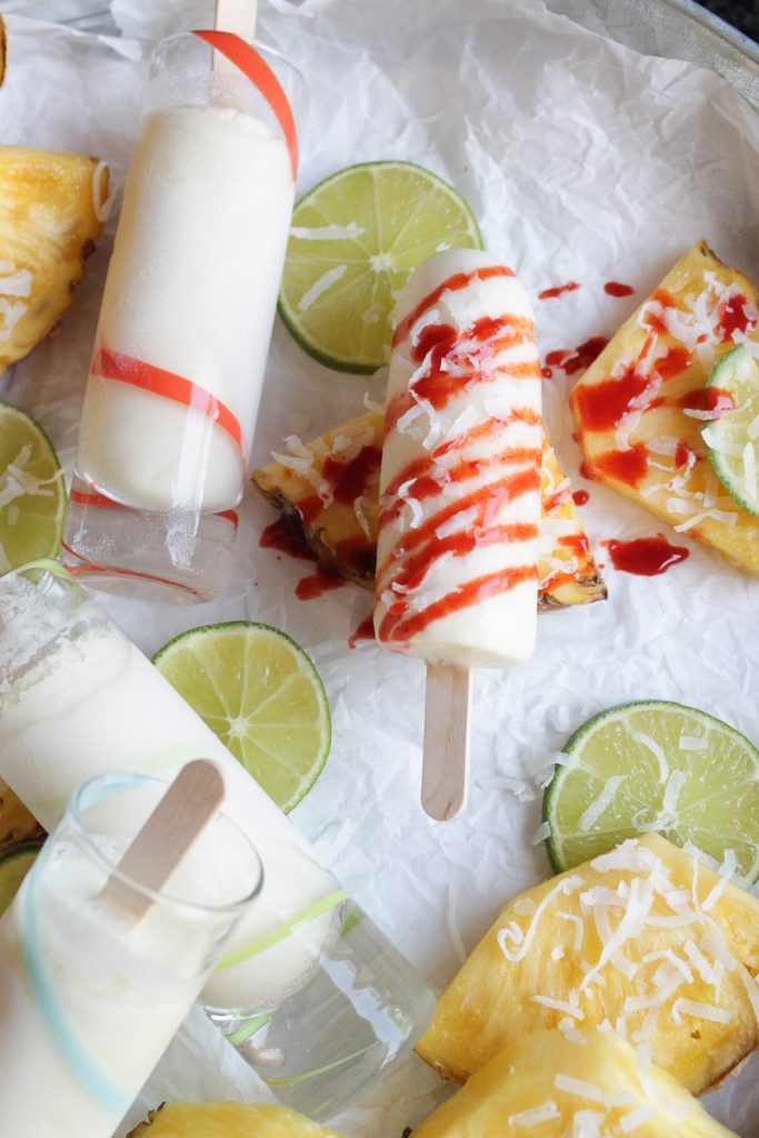 Pineapple and lime slices with shot glass size coconut pineapple and lime popsicles, drizzled with chamoy sauce.
