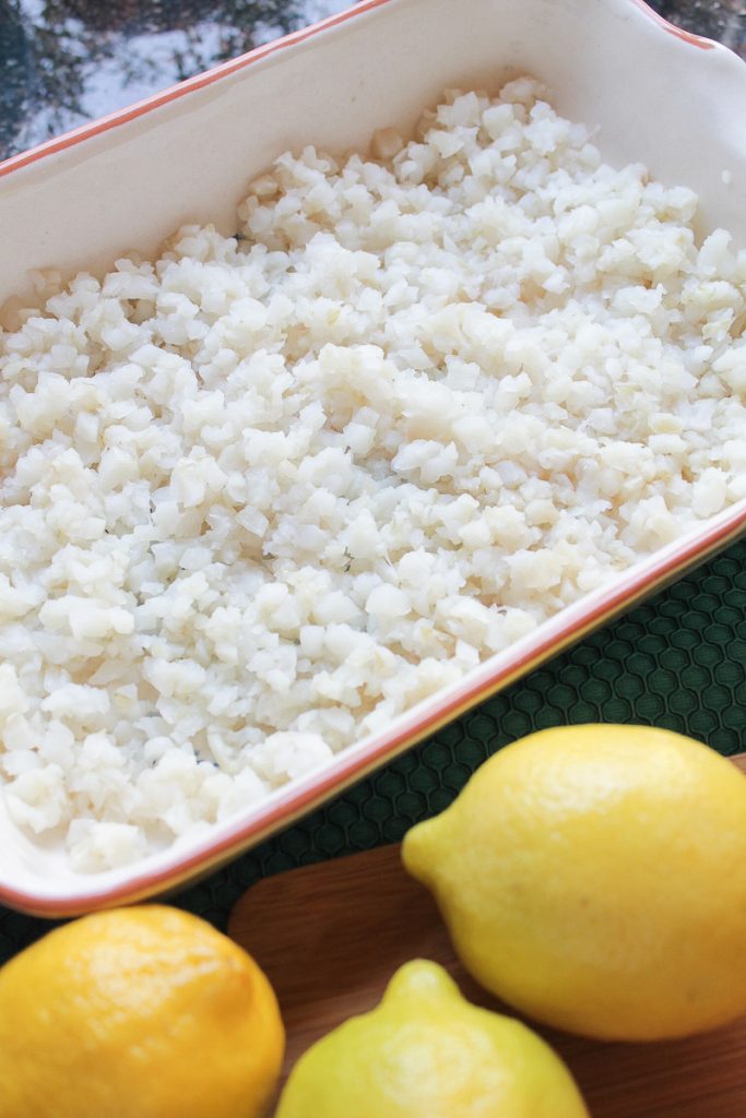 Diced sole fish in a baking dish with three lemons on the side.