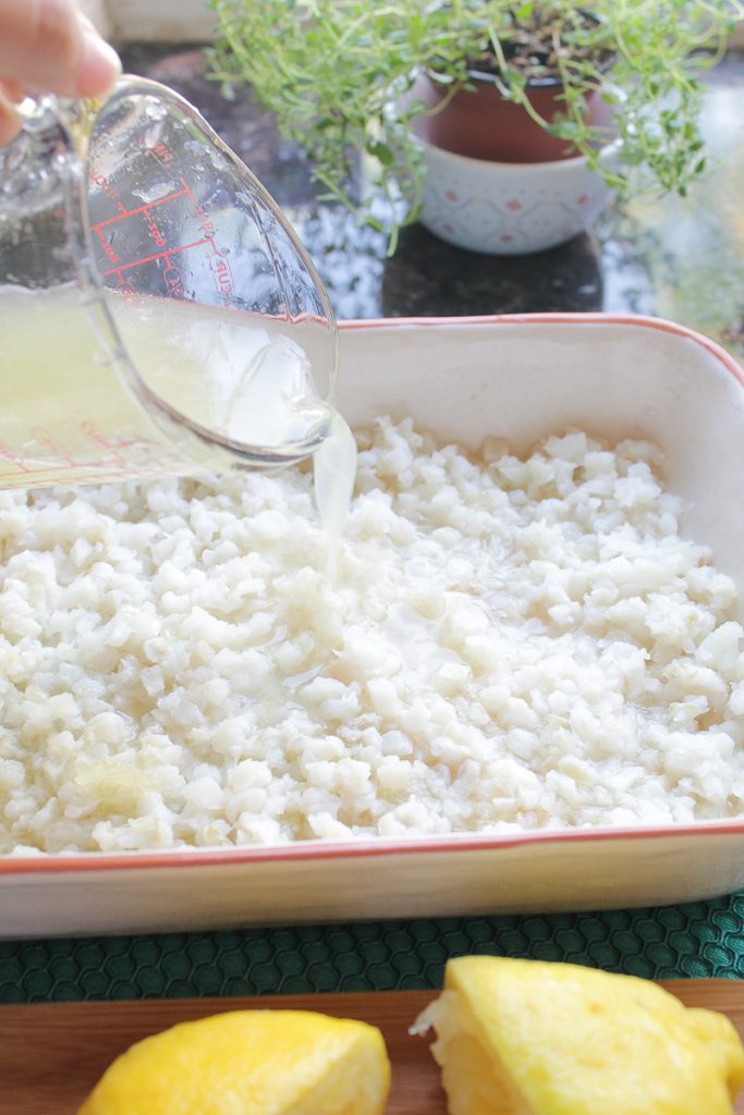 Fresh squeezed lemon juice being poured over diced sole fish in a baking dish.