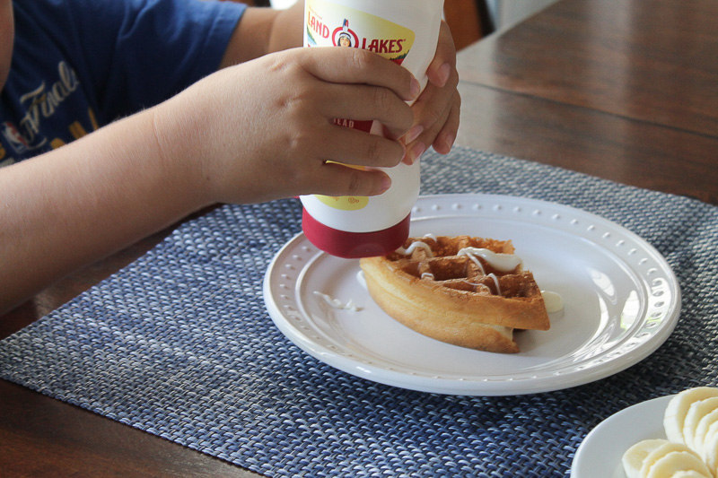 3 Tips To Avoid Soggy Waffles A boy's hands squeezing Land O Lakes Soft Squeeze™ Spread onto a waffle.