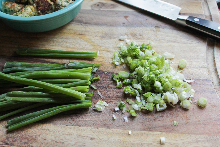 scallion onions chopped on a wooden cutting board.
